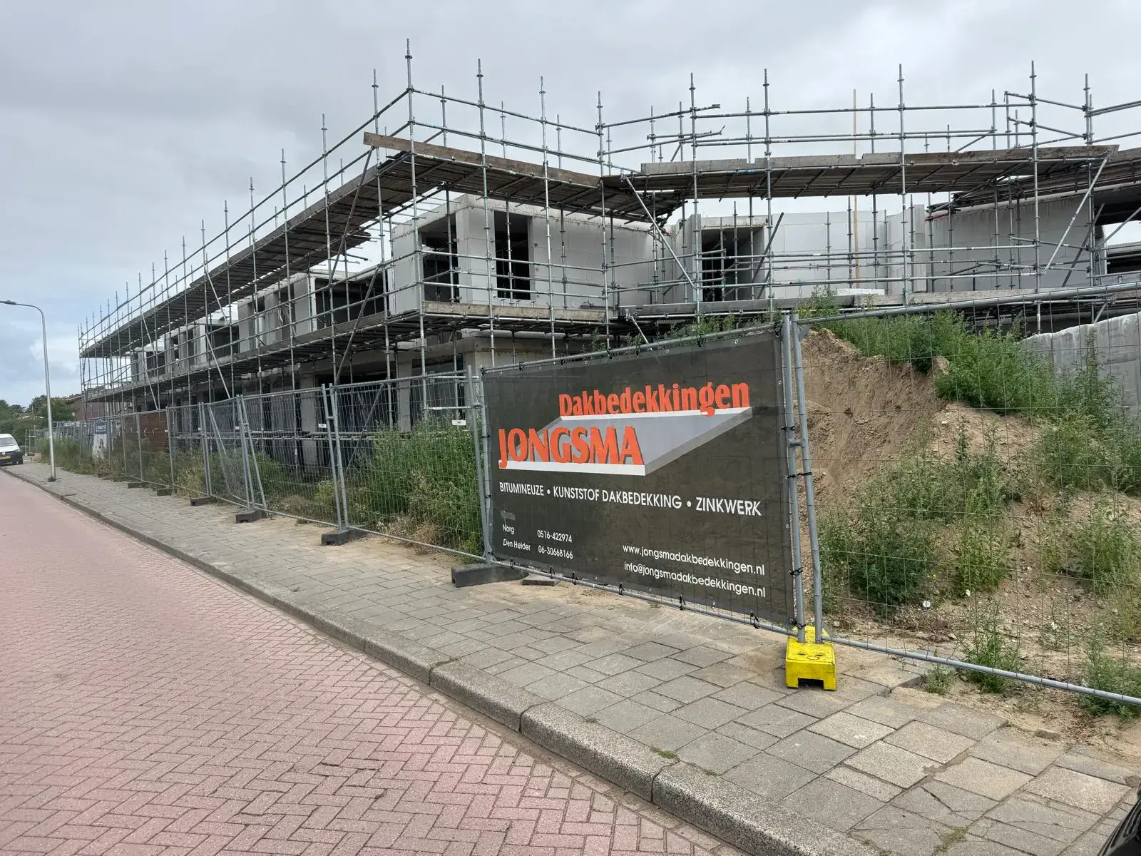 Nieuwbouw in de steigers met een spandoek van Jongsma