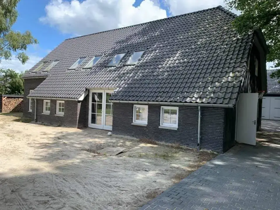Opgeleverd pannendak met zwarte pannen op een schuurwoning